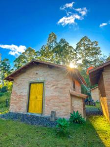 ein kleines Backsteinhaus mit gelber Tür in der Unterkunft CAFOFO DA GIO in Conceição da Ibitipoca