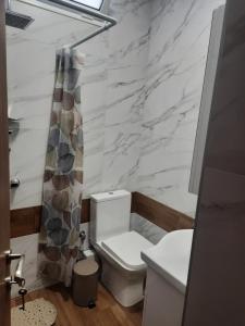 ein Badezimmer mit einem weißen WC und einer Marmorwand in der Unterkunft Sweet Maison Apartment in Paralia Katerinis