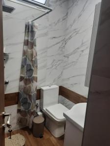 a bathroom with a white toilet and a marble wall at Sweet Maison Apartment in Paralia Katerinis