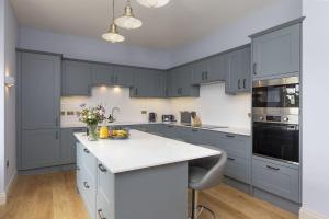 cocina con armarios azules y encimera blanca en East Wing, en Thornhill