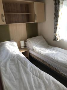 two beds in a small room with a window at Holiday Caravan, Pebble Bank in Wyke Regis