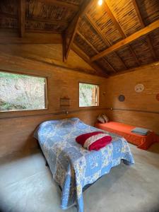 ein Schlafzimmer mit einem Bett in einer Holzhütte in der Unterkunft CAFOFO DA GIO in Conceição da Ibitipoca