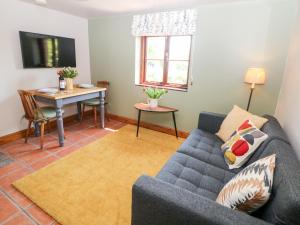 a living room with a couch and a table at Old Post Office Barn in Leek