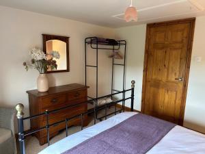 a bedroom with a bed and a dresser and a mirror at Old Post Office Barn in Leek