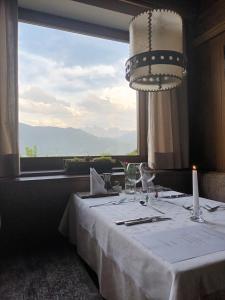 a dining room with a white table with a large window at Biogasthaus Plonerhof "sweet Dolomites view" in Bressanone
