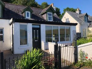 uma casa com portas de vidro e uma cerca em The Old Post Office House BnB em Balmacara