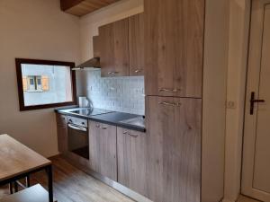 una cocina con armarios de madera y fregadero en Appartement chaleureux, en Aime La Plagne