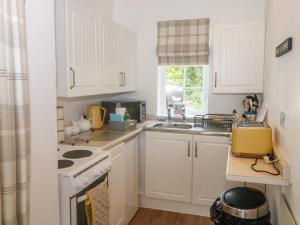 a kitchen with white cabinets and a stove top oven at Rose Cottage in Paignton