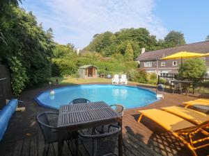 a swimming pool with a table and chairs and a picnic table at Rose Cottage in Paignton