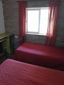1 dormitorio con 2 camas y una ventana con cortinas rojas en La Escondida en Villa del Dique
