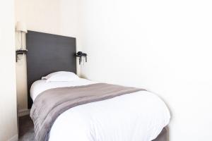 a bedroom with a white bed with a black headboard at Hôtel De La Plage in Le Chambon-sur-Lignon