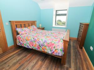 a bedroom with a bed with a floral comforter at Lack Cottage in Tralee
