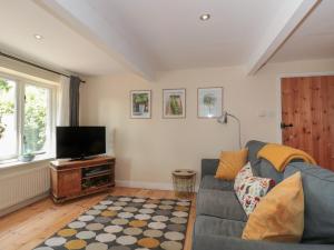 a living room with a couch and a flat screen tv at Nuthatch in Honiton