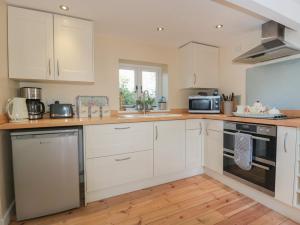 a kitchen with white cabinets and a wooden floor at Nuthatch in Honiton