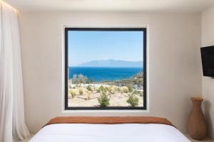 KOIA All - Suite Well Being Resort - Adults Only في Ágios Fokás: غرفة نوم مع نافذة مطلة على المحيط