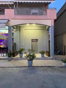 un edificio rosa con balcón y macetas en Sofita Luxury Apartment en Paralía