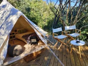 Zelt mit einem Bett und zwei Stühlen auf einer Terrasse in der Unterkunft Gaia Double bell tent in Swellendam
