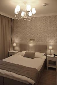 a bedroom with a large bed and a chandelier at Apartament nad Zegrzem 206 Luksus in Serock