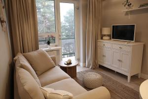 a living room with a white couch and a television at Apartament nad Zegrzem 206 Luksus in Serock