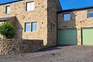 a brick house with two green garage doors at Coolams in Ingleton