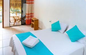 a bedroom with a large white bed with blue pillows at Casa Yoo Bigu Mazunte in Mazunte