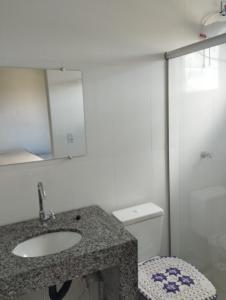 a bathroom with a sink and a toilet and a mirror at Residencial Casa Grande Apto 04 in Santa Cruz Cabrália