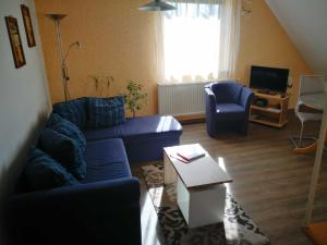 a living room with a blue couch and a table at Ruegen_Fewo 28 a in Lobbe