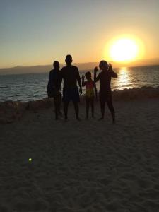 a group of people walking on the beach at sunset at Dead Sea Jordan Sea View Samarah Resort Traveler Award 2024 winner in Sowayma