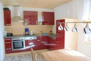 a kitchen with red cabinets and a sink and a table at Ruegen_Fewo 292 in Ummanz