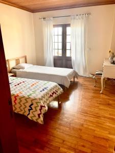 two beds in a room with wooden floors and a window at Casa da Pedra Guest House in Torres Vedras