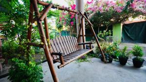 a swing in a garden with flowers and plants at HUAQIAO HOME 侨之家免费供早餐free breakfast served in Semporna