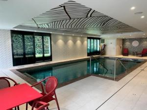 a large swimming pool with a red table and chairs at Domitys L'Orangerie in Sens
