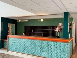 a lobby with a blue counter with flowers on it at Domitys L'Orangerie in Sens