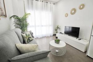 a living room with a couch and a tv at Apartamento Bajo 1 Marjal playa centro de Guardamar in Guardamar del Segura
