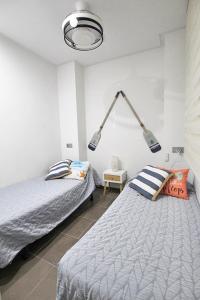 a bedroom with two beds and two lights on the wall at Apartamento Bajo 1 Marjal playa centro de Guardamar in Guardamar del Segura