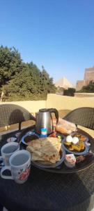 een tafel met een dienblad met ontbijtproducten erop bij Ramses Guest House in Caïro