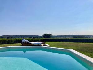 a swimming pool with a table and a bench in a field at Herdade da Burquilheira Family Retreat in Alcáçovas