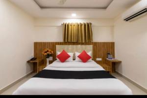 una camera da letto con un grande letto con cuscini rossi di NEW ROYAL LODGE a Mangalore