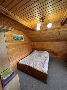 Cette chambre comprend un lit dans une cabane en bois. dans l'établissement Садиба Криниченька, à Yaremtche