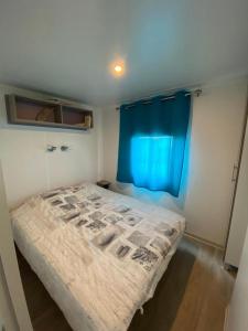 Dormitorio pequeño con cama con cortina azul en MH148 camping TOHAPI NOVELA - Mobil home 6p climatisé -, en Port-la-Nouvelle