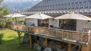 una terrazza in legno con ombrelloni di fronte a un edificio di Superbe ferme rénovée en chalet de luxe en PLEINE NATURE a Barcelonnette