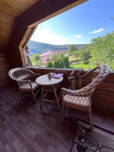 - une terrasse couverte avec 2 chaises, une table et une fenêtre dans l'établissement Садиба Криниченька, à Yaremtche