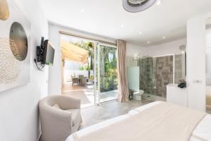 ロス・ジャノス・デ・アリダネにあるBayton Houseの白いベッドルーム(ベッド1台付)、ガラスのスライドドアが備わります。