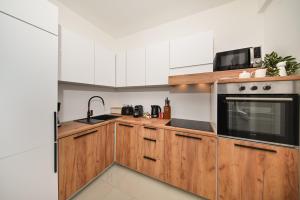 a kitchen with wooden cabinets and a microwave at Apartman Nella with sea wiew in Zadar