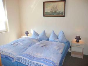 a bedroom with a blue bed with a picture on the wall at Ruegen_Fewo 102 in Sagard