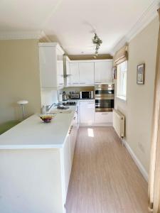 a kitchen with white cabinets and a wooden floor at Golf Court View, Elie in Elie
