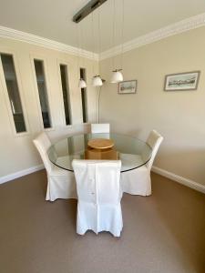 a dining room with a glass table and white chairs at Golf Court View, Elie in Elie