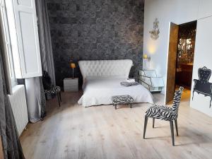 a bedroom with a white bed and two chairs at PIED A TERRE DE CHARME in Albi