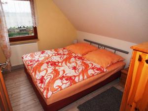 ein Bett mit einer orangefarbenen und weißen Bettdecke und einem Fenster in der Unterkunft Rügen Fewo 79 in Putbus