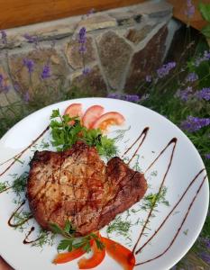 a piece of steak on a white plate with vegetables at Chudodievo in Chynadievo Mini-Hotel in Chynadiyovo